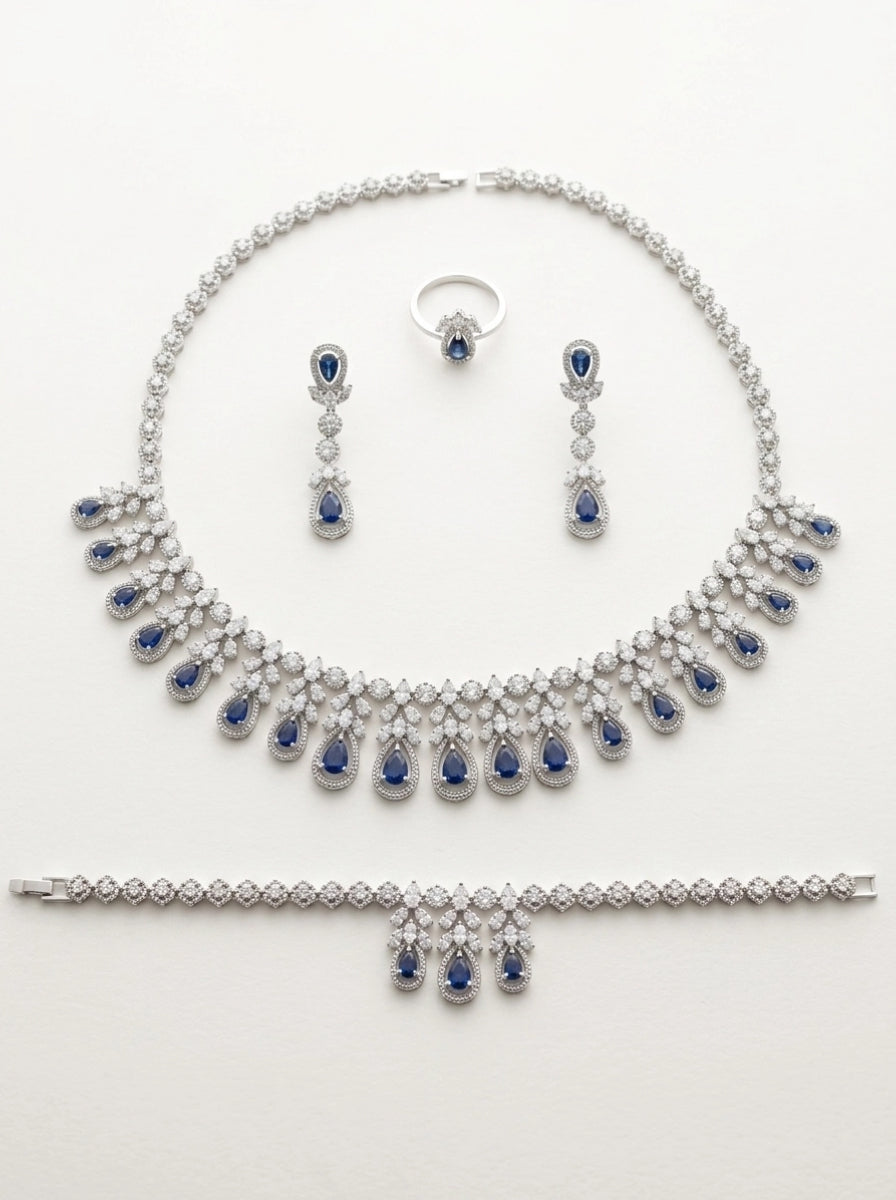 Flat lay of the Blue Teardrop Elegance set — necklace, earrings, ring and bracelet on white background